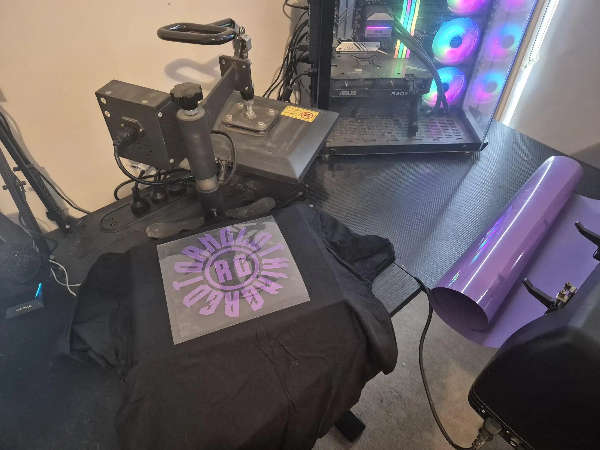 Black and purple heat press machine with a design on the shirt.