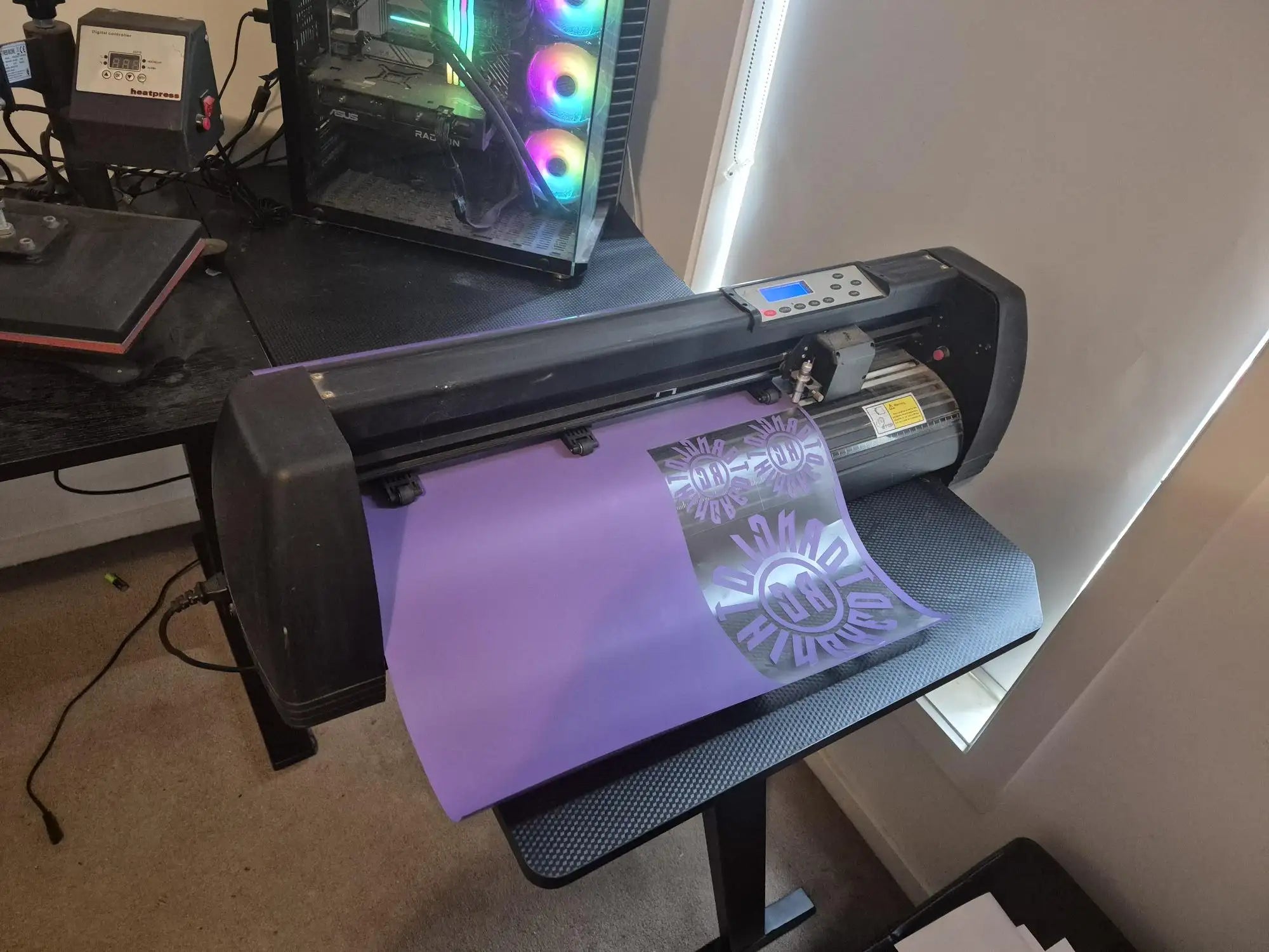 Purple vinyl cutter with black frame and digital display panel, likely a cricut explore model.