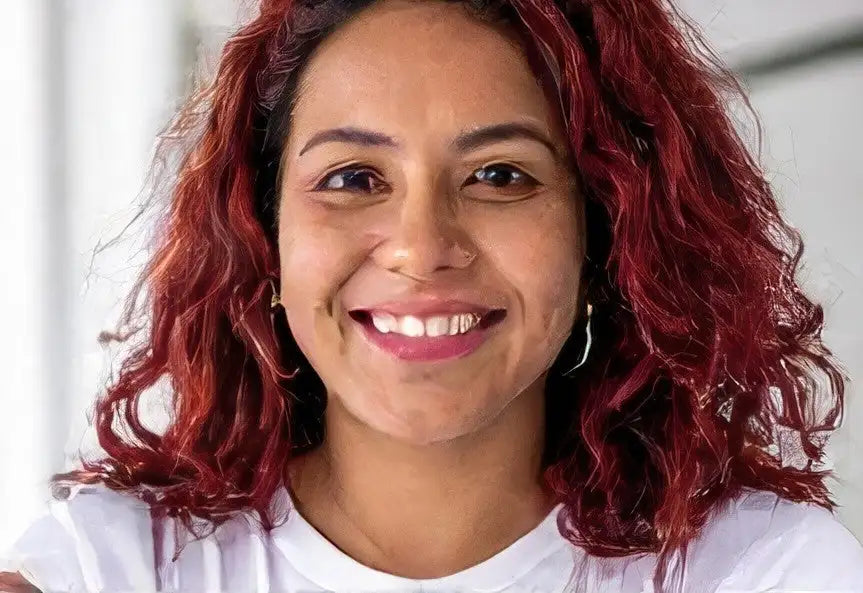 Red curly hair woman’s white t-shirt with hoop earrings.